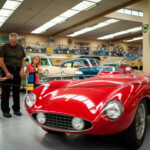 classic car parked in a museum with father and son looking at it