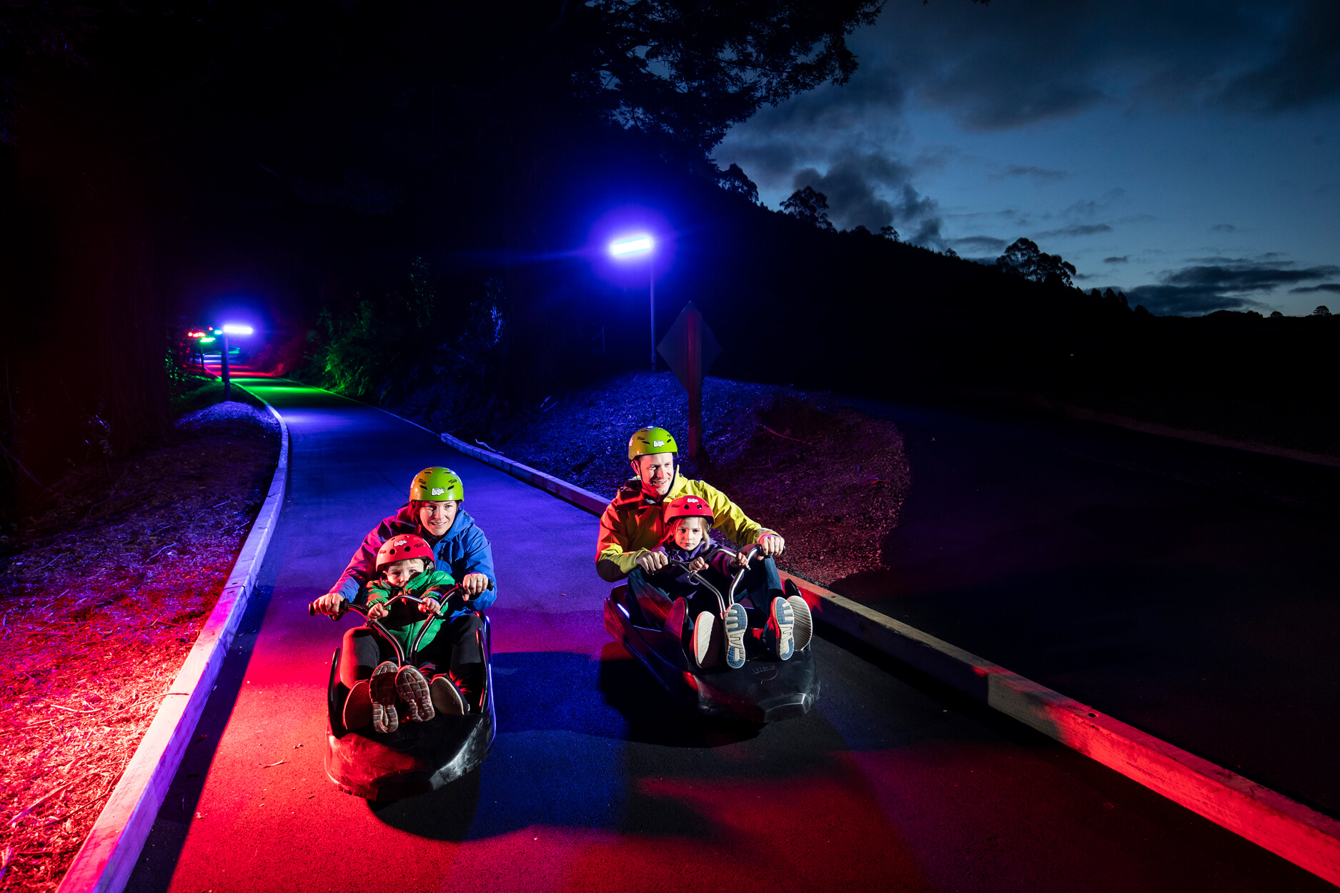 skyline rotorua luge a family riding down the luge tracks at night 1